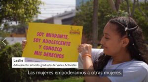 Leslie, adolescente activista sosteniendo un cartel que dice Soy Migrnate, soy adolescente y conozco mis derechos